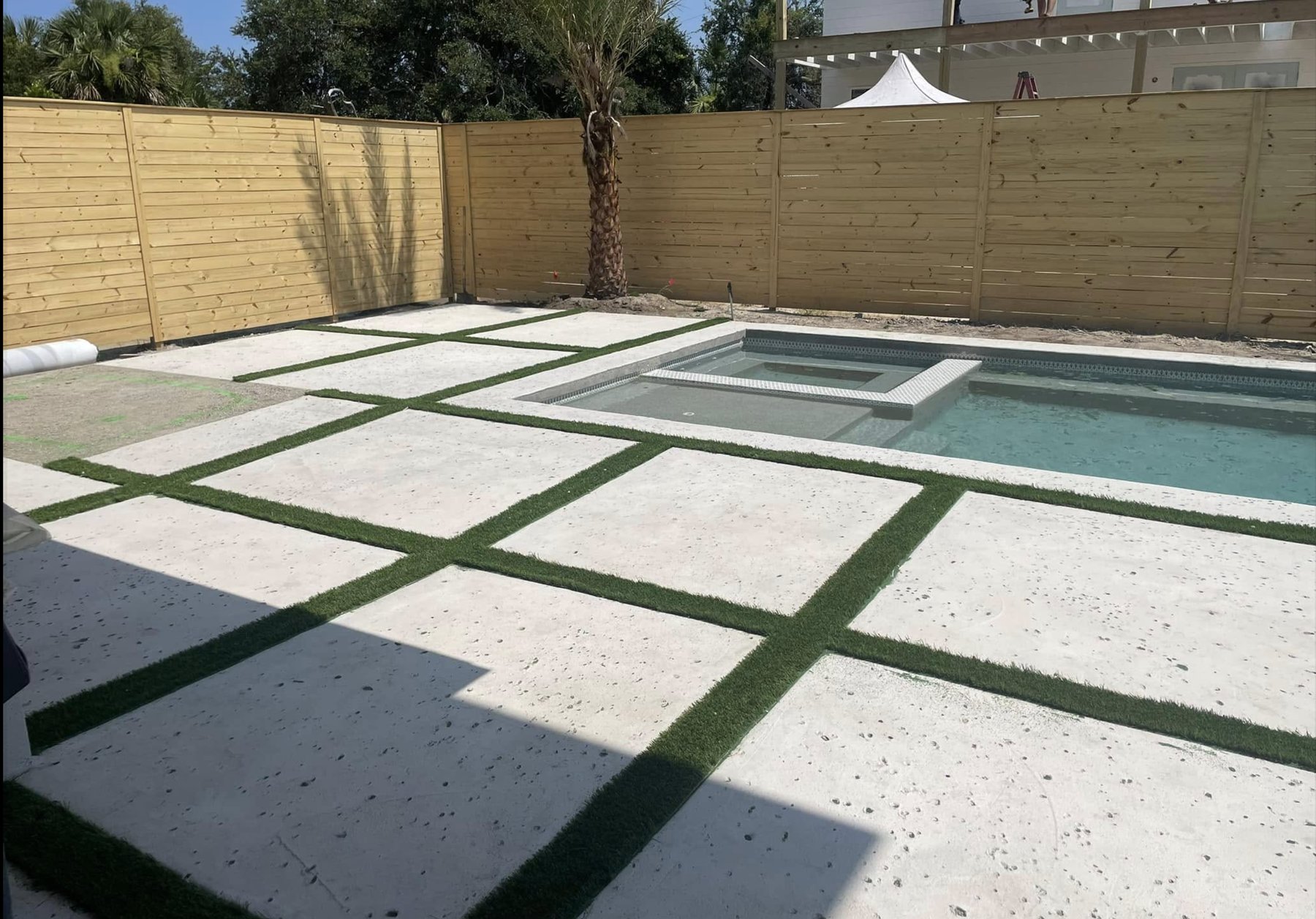 Fresh artificial turf lawn with crisp paver border installed by Baker Greens in St. Augustine