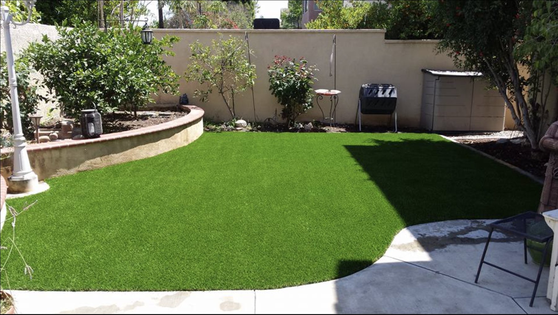 Same backyard after: fresh artificial turf lawn with clean curved edge