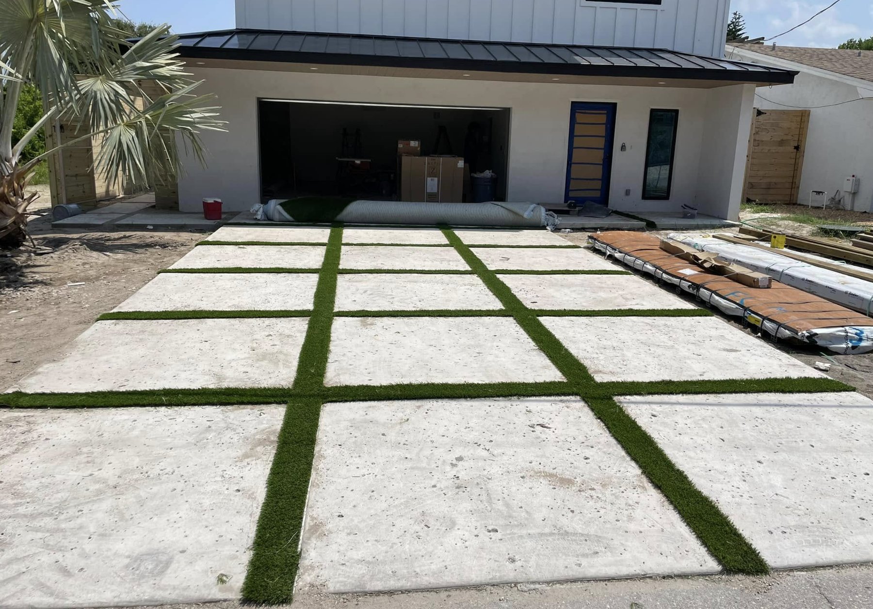 Modern paver driveway with artificial turf strips between concrete slabs